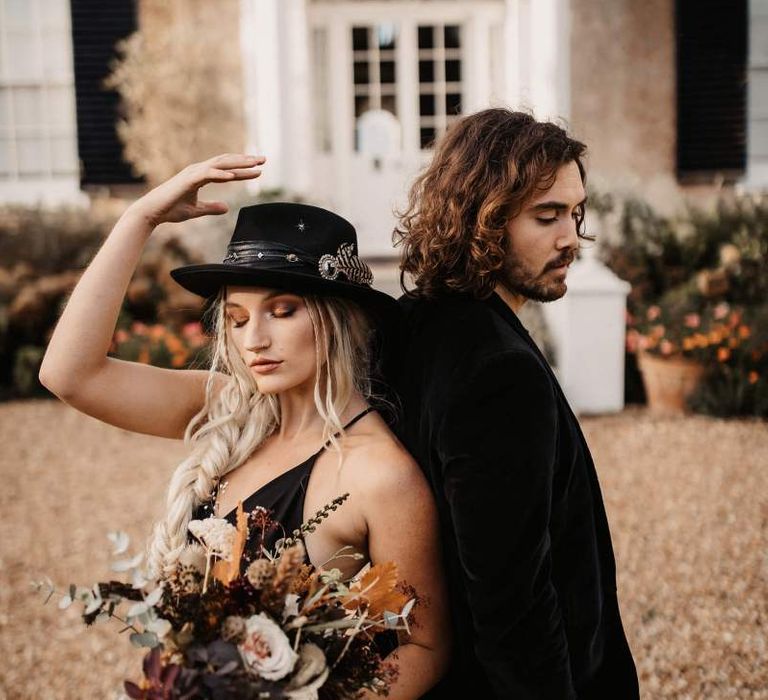 Halloween wedding with bride in black dress and hat and groom in  velvet jacket