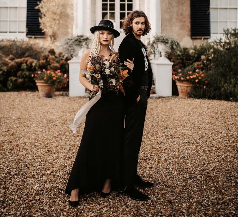 Stylish bride and groom in black wedding dress and hat for Halloween wedding  shoot