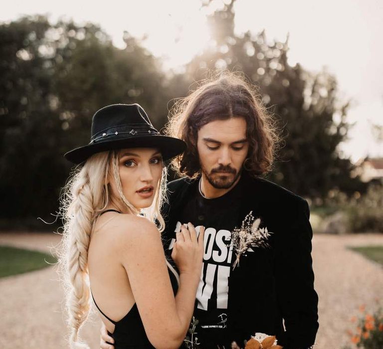 Cool bride and groom in black wedding dress, hat T-shirt and blazer for Halloween wedding  shoot