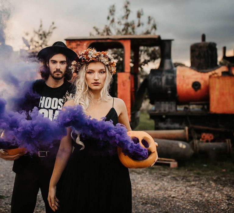 Alternative bride and groom holding smoke bombs at Halloween wedding