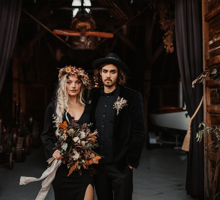 Halloween wedding inspired shoot with bride and groom in black outfits holding Autumn flowers