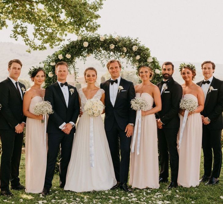 Wedding Party Portrait in Front of a White and Green Floral Arch