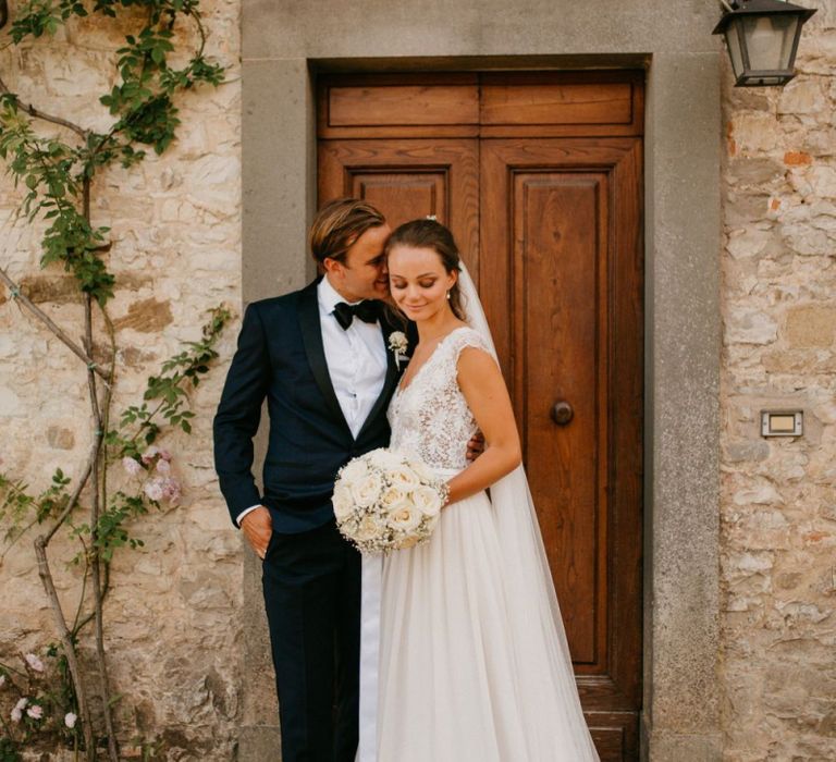 Bride in Bespoke Wedding Dress with Pure White Bouquet and Groom in Black Tie Suit