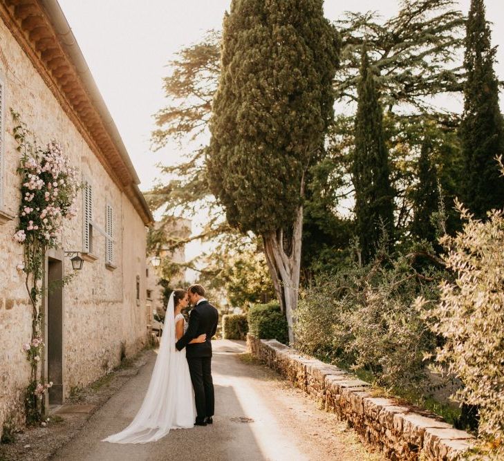 Bride in Bespoke Wedding Dress and Groom in Black Tie Suit Posing Next to Their Italian Castle Wedding Venue