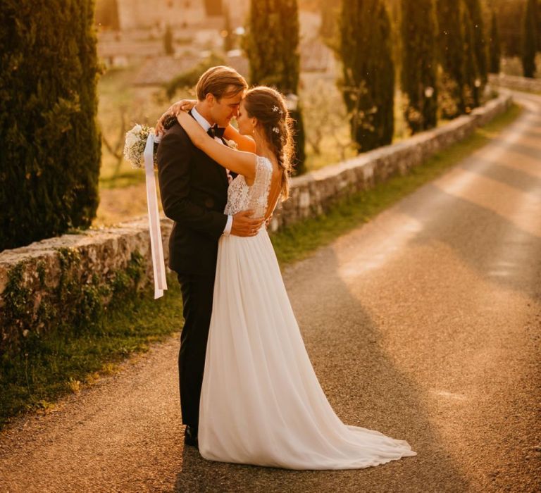 Golden Hour Portrait with Bride in Bespoke Wedding Dress and Groom in Tuxedo and Bow Tie Embracing