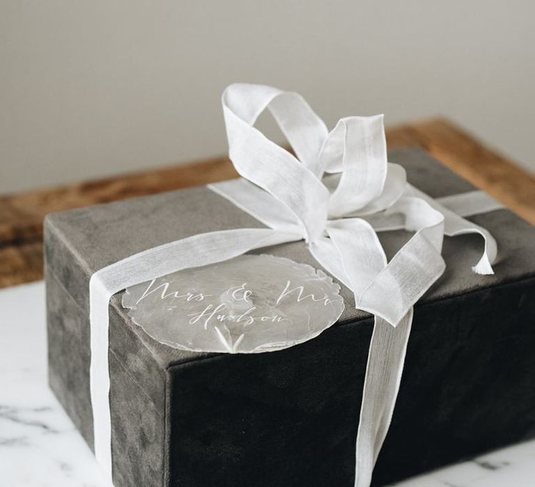 Grey Gift Box Tied with White Ribbon and Clear Gift Tag