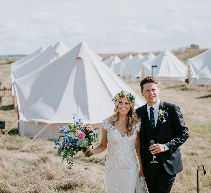 Bride in Lace Watters Wedding Dress and Groom in Hugo Boss Suit Standing in Front of Bell Tent