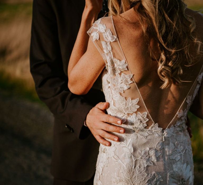 Groom Embracing His Bride in a Lace Watters Wedding Dress