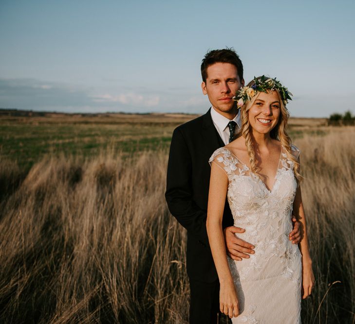 Groom in Hugo Boss Suit and Bride in Lace Watters Wedding Dress Standing in a Field