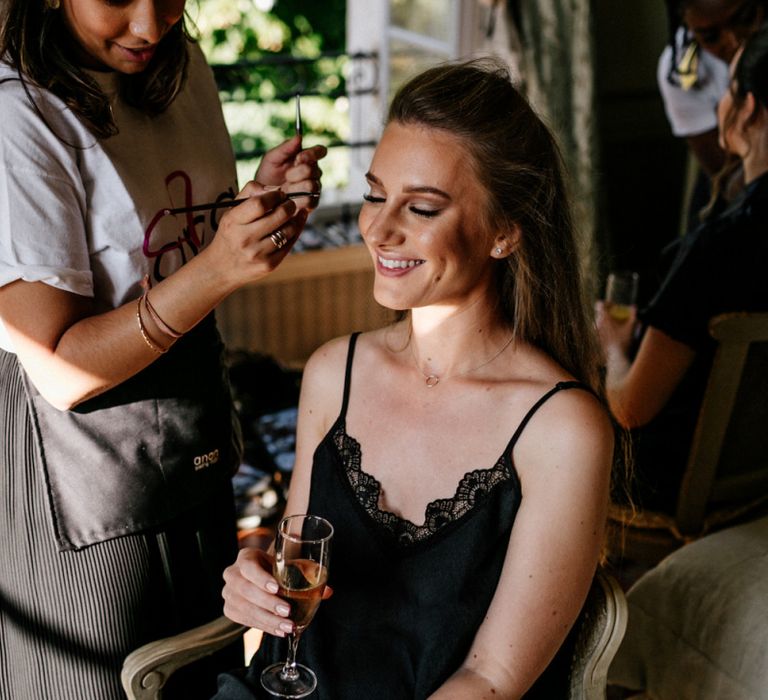 Wedding Morning Bridal Party Preparations with Bridesmaid in Black Slip Having Her Makeup Done