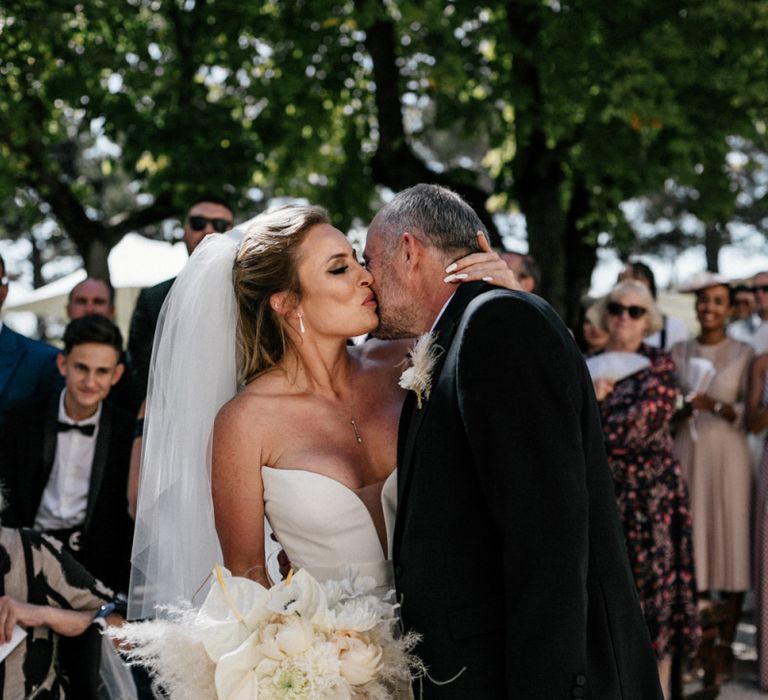 Bride in a Wedding Dress with Feathers Kissing Her Dad at the Altar