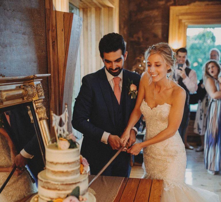 Bride and Groom Cut Wedding Cake At Rustic Wedding