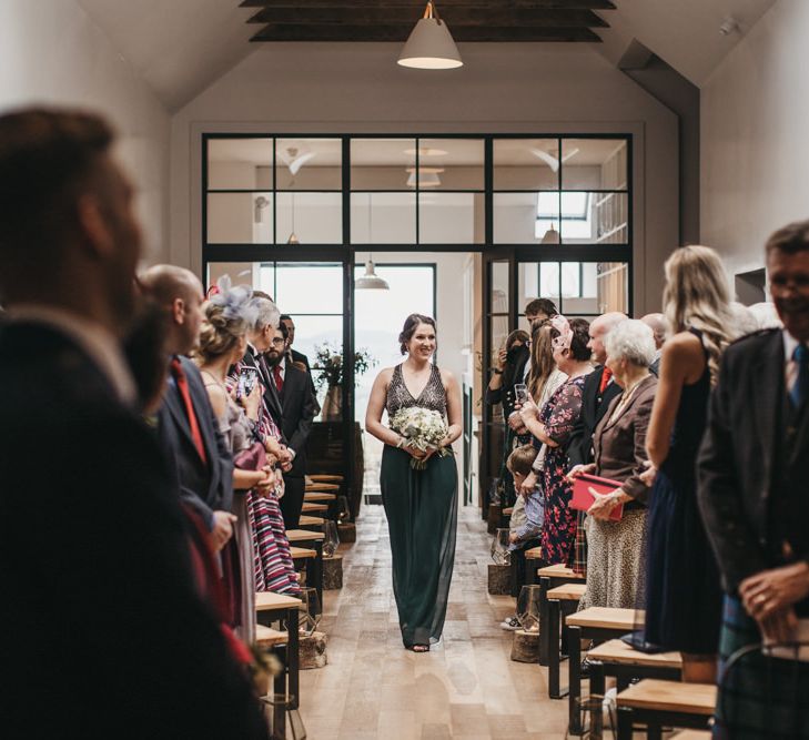 Bridesmaid walks up aisle during ceremony at Guardswell Farm