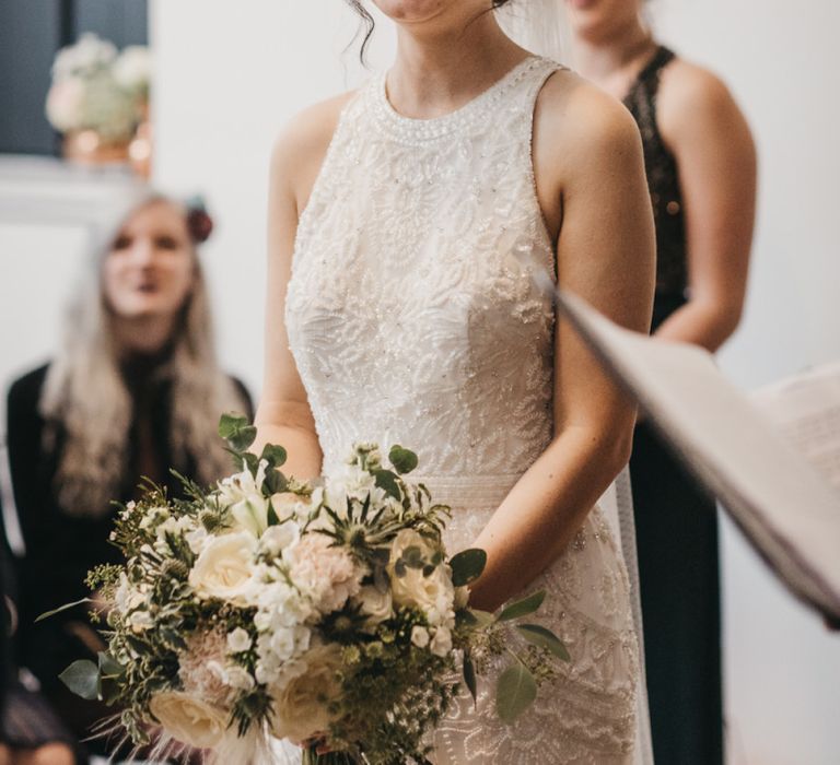 Bride with updo and hair accessory clutching white wedding bouquet