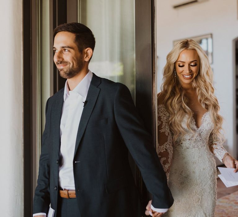 Bride and groom hold hands and read notes before their wedding ceremony