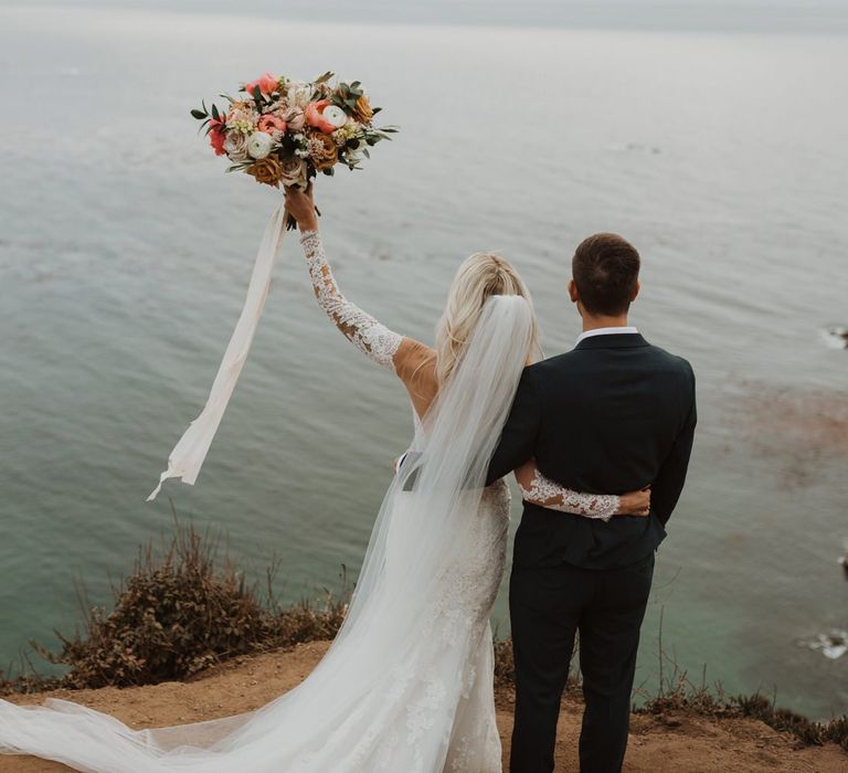 Bride holding up her coral and white wedding bouquet at California elopement