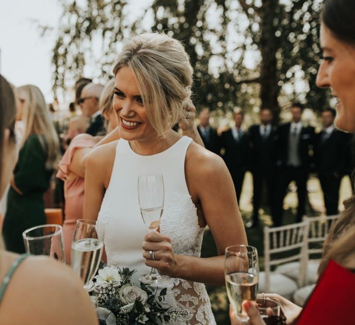 Bride sips champagne whilst mingling with guests during Hyde House wedding