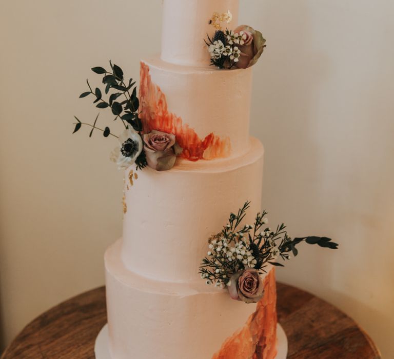 Pink wedding cake with flower and foliage decor