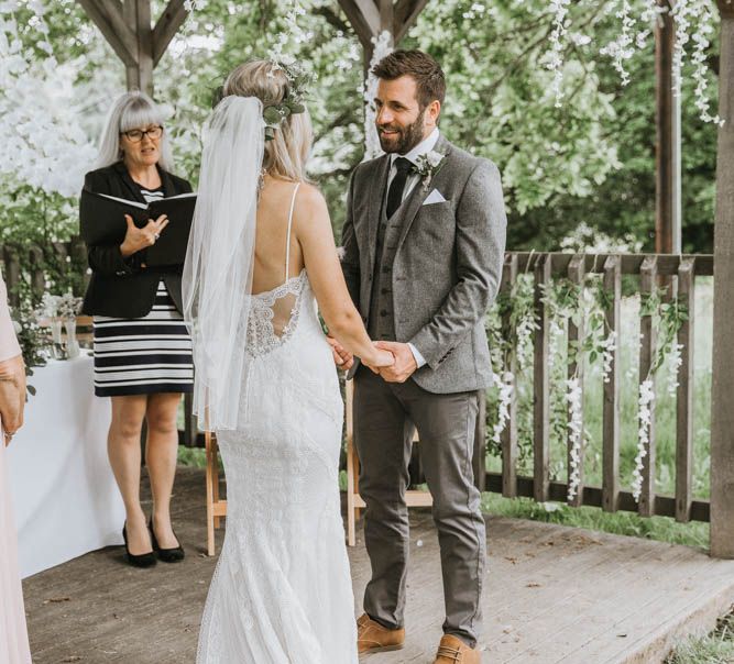 Bride in Lace Wedding Dress and Groom in Wool Suit Exchanging Vows During Outdoor Wedding Ceremony