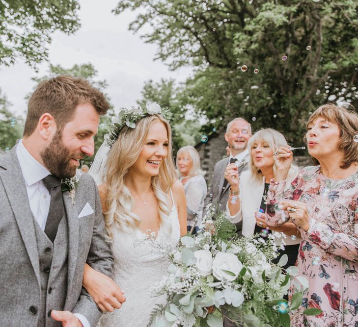 Bride in Lace Wedding Dress and Groom in Wool Suit During Confetti Moment