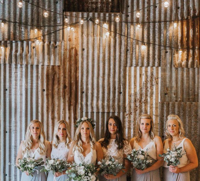 Bridal Party Portrait Under Festoon Lights with Bride in Lace Wedding Dress and Flower Crown and Bridesmaids in Separates