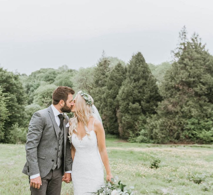 Bride in Lace Wedding Dress and Flowers Crown and Groom in Brown Wool Suit Kissing