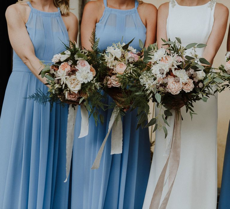 Bride and Bridesmaids in Blue Halterneck Dresses Holding Their Bouquets