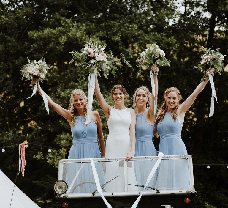 Bridal Party Portrait with Bridesmaids in Blue Halterneck Dresses and Bride in Makaella Bridal Wedding Dress Holding up Their Bouquets in The Wedding Car