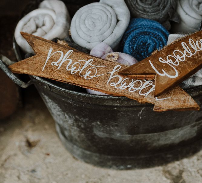 Metal Basket Filled with Rolled Blankets and Wooden Arrow Wedding Signs