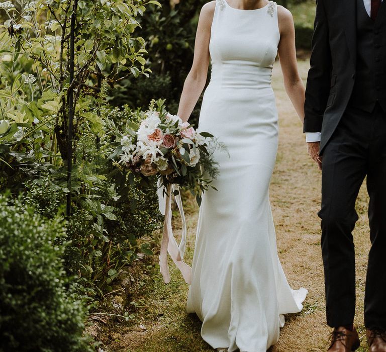 Bride in High Neck Mikaella Bridal Fitted Wedding Dress and Groom in  Clifton Suit Holding Hands