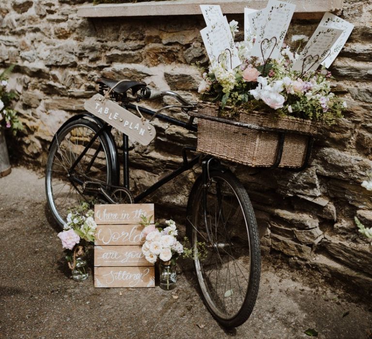 Vintage Bicycle Basket Filled with Flowers as a Wedding Table Plan with Wooden Signs