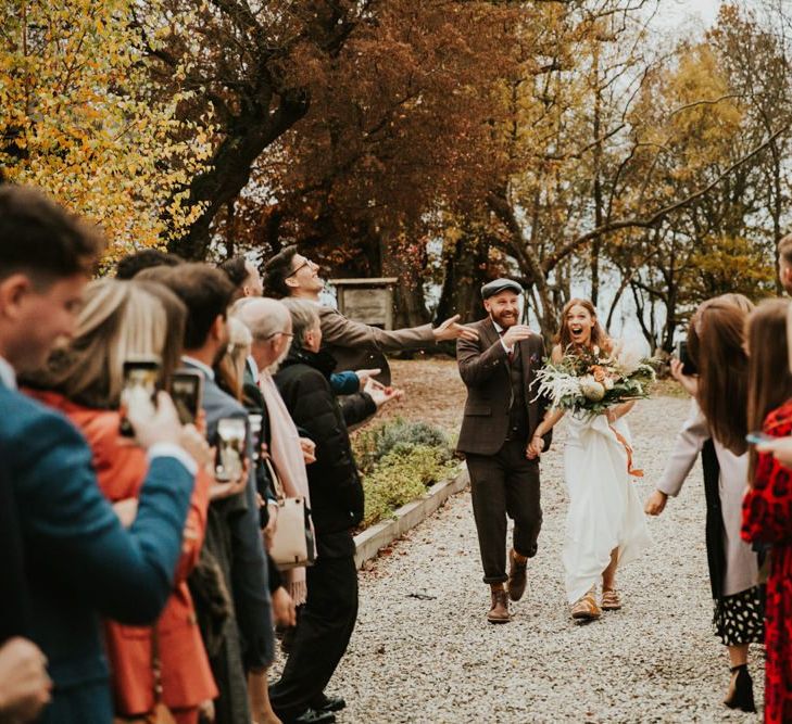 Confetti exit fir bride and groom with bridesmaids wearing bridesmaid jumpsuit