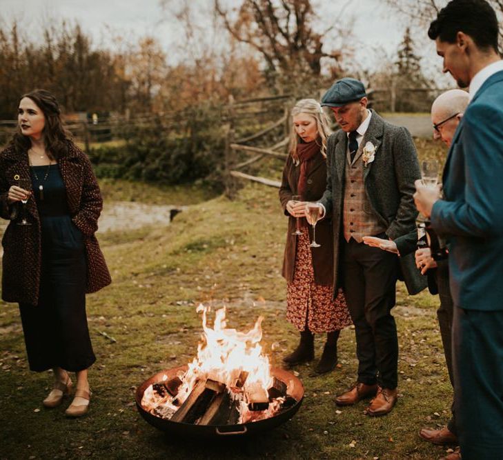 Guests gather round the open fire at Winter wedding