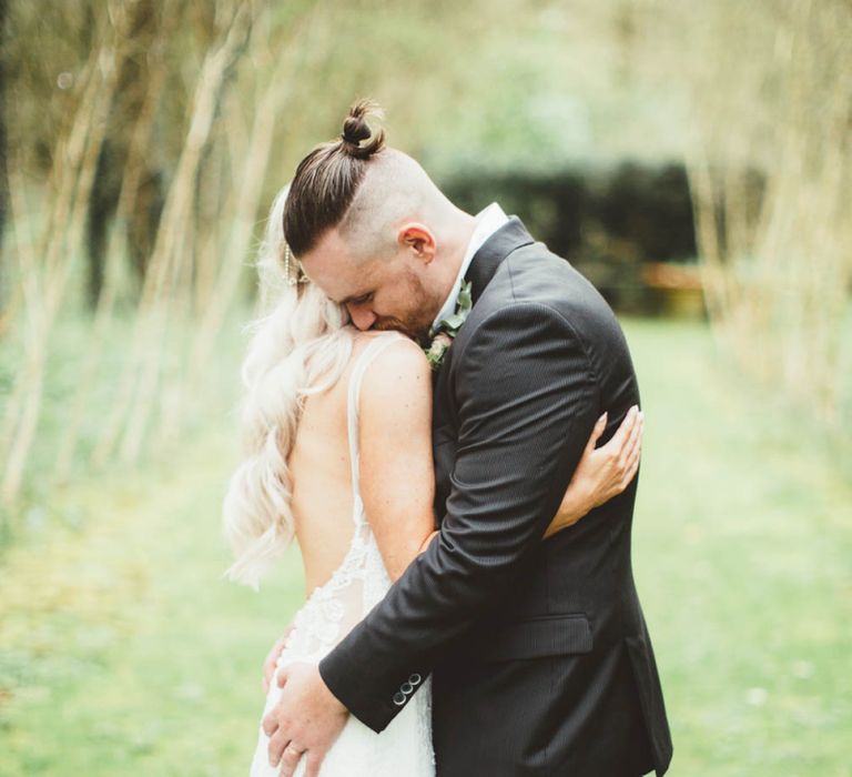 Bride in Danni Made With Love Bridal Wedding Dress and Groom in Reiss Suit Embracing in the Countryside