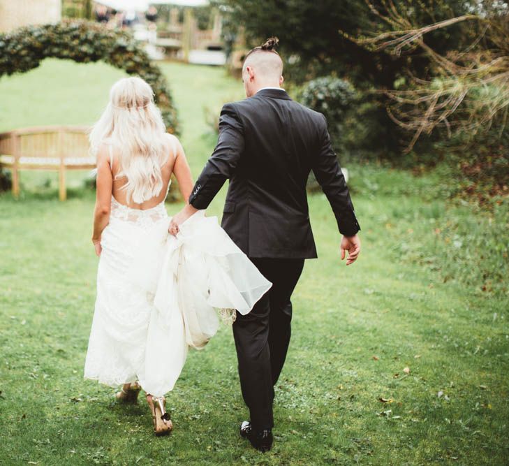 Bride in Danni Made With Love Bridal Wedding Dress and Groom in Reiss Suit Walking Through the Gardens