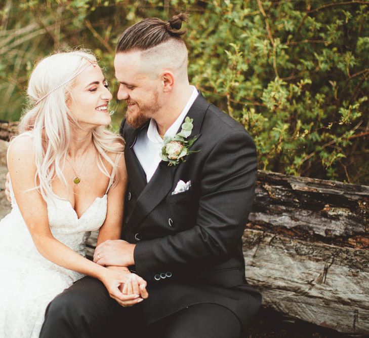 Bride in Danni Made With Love Bridal Wedding Dress and Groom in Reiss Suit Cuddling on a Log