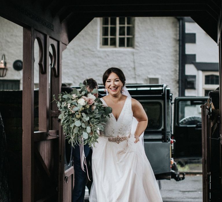 Smiling bride in blush pink wedding dress arriving at the church wedding ceremony