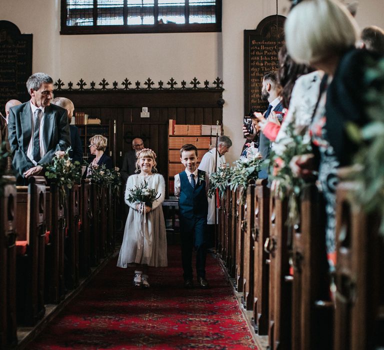 Flower girl and page boy walking down the aisle at the church wedding ceremony