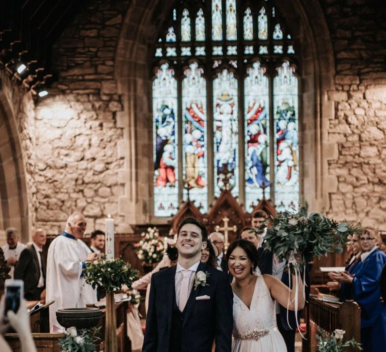 Bride in blush wedding dress and groom walking up the aisle as husband and wife