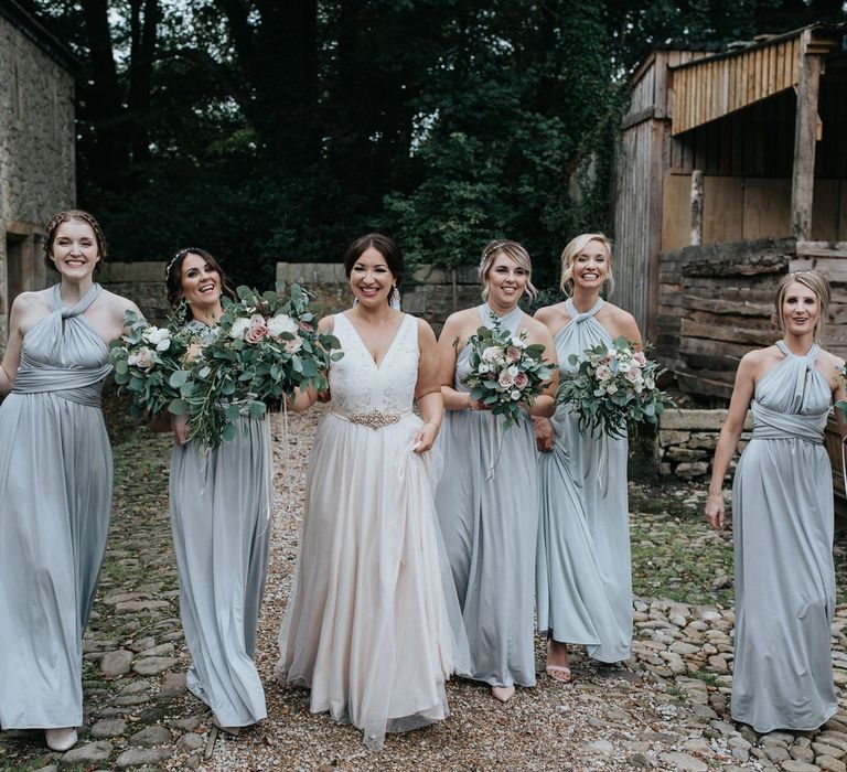 Bridal party portrait with bride in blush wedding dress and bridesmaids in grey multiway dresses