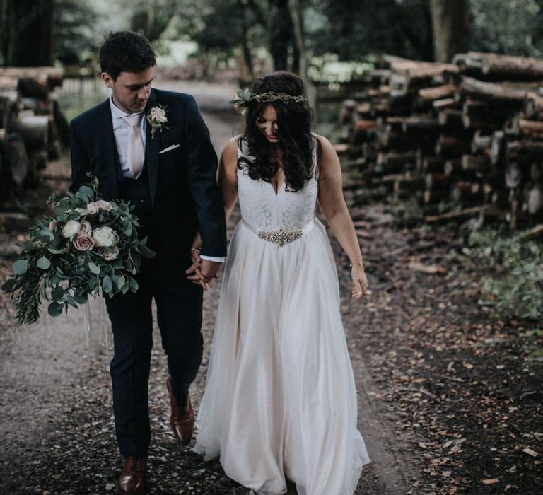 Boho bride in blush wedding dress and flower crown with groom holding her bouquet