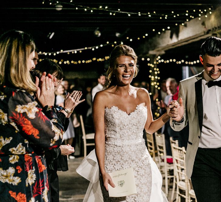 Bride in Tara Keely Wedding Dress and Groom in Grey Tuxedo Jacket Walking Up the Aisle After Saying I Do