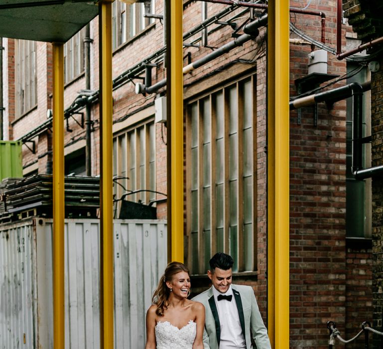 Bride in Off the Shoulder Tara Keely Wedding Dress with Detachable Organza Skirt and Groom in Grey Tuxedo Jacket