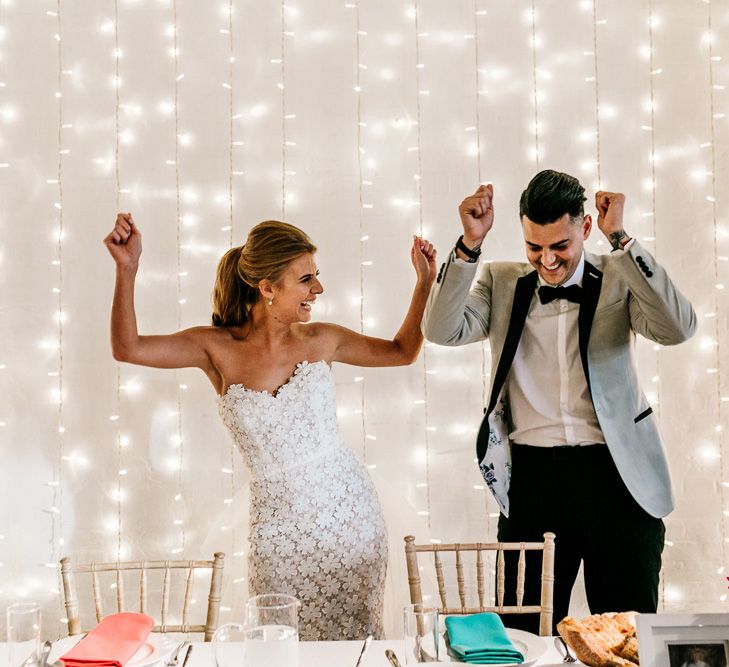 Bride and Groom Standing In Front of a Fairy Light Backdrop