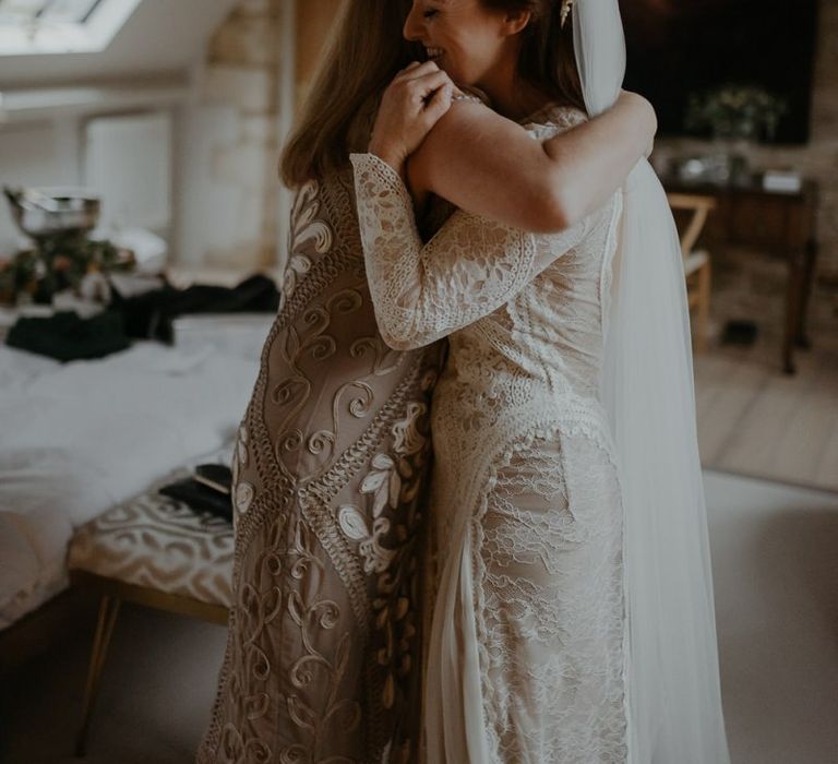 Bride and bridesmaid hugging on wedding morning