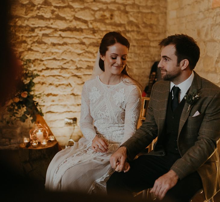 Bride in lace wedding dress and groom in wool suit holding hands