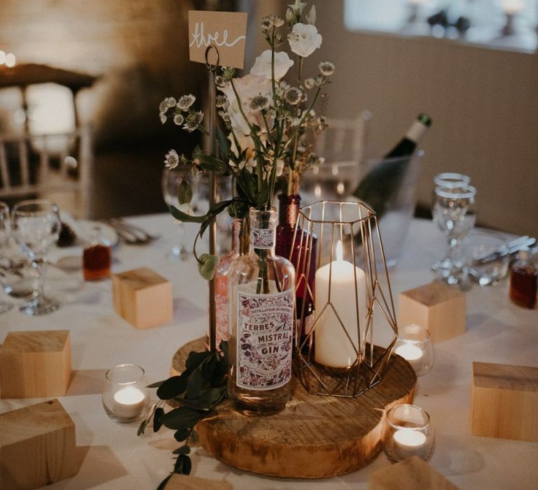 Rustic centrepiece decor with tree slice, terrarium, gin bottles and flowers