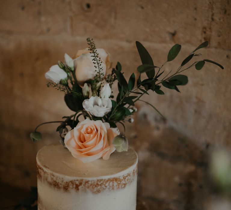 Small semi naked wedding cake with flower topper