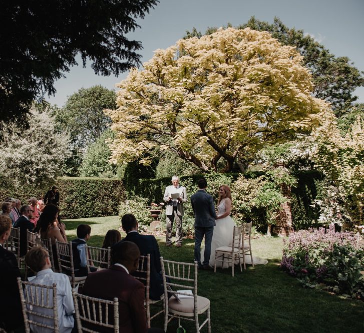 Bride and groom during outdoor ceremony with Prosecco wall