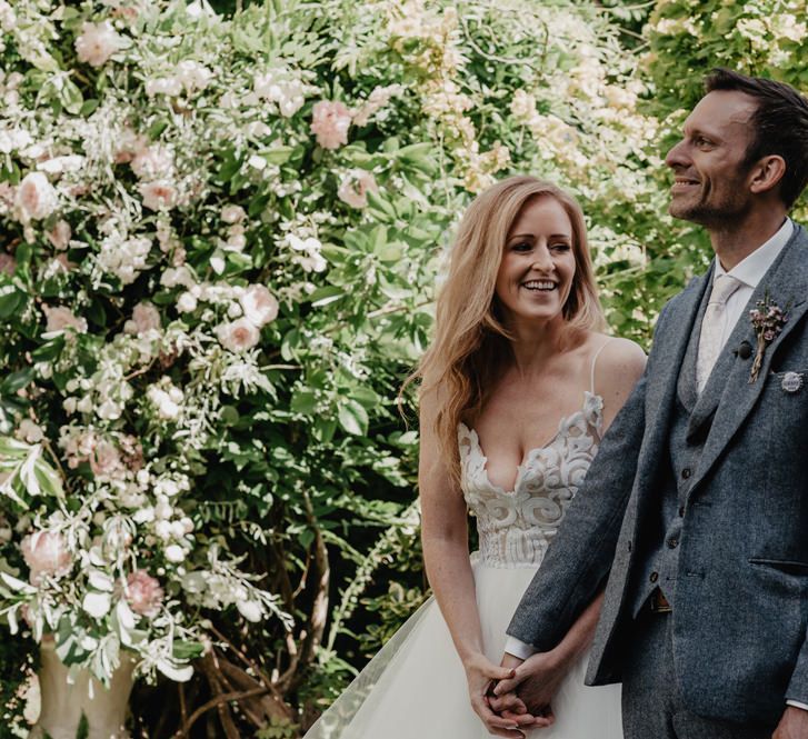 Bride and groom during outdoor wedding in woolen suit  with Prosecco wall